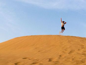 Low angle view of woman jumping against clear sky