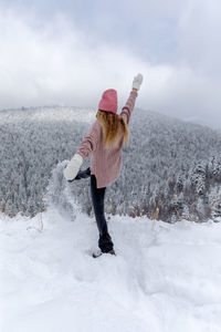Woman standing on snow covered land against sky