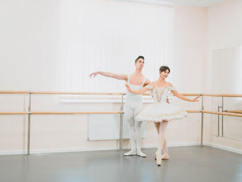 Full length of man and woman practicing ballet dance in studio