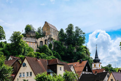 Houses by trees and buildings against sky