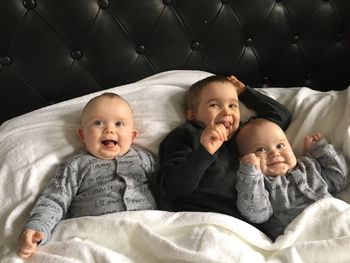 Happy siblings lying on bed at home