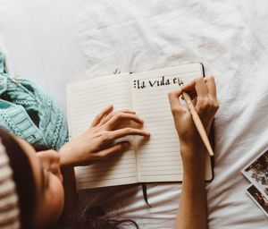 High angle view of woman hand with text on bed