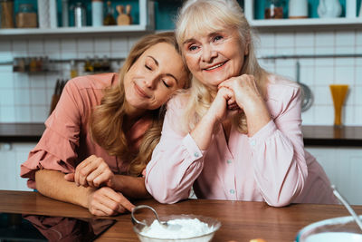 Cheerful mother and daughter embracing at kitchen