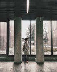 Woman standing by glass window of building