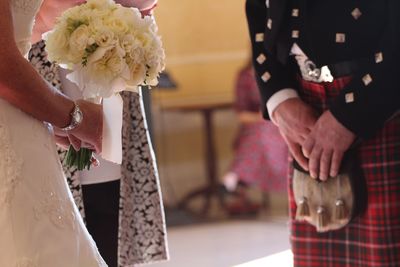 Midsection of man by woman holding bouquet