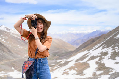 Young woman photographing against sky