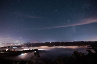 Scenic view illuminated landscape against star field at night