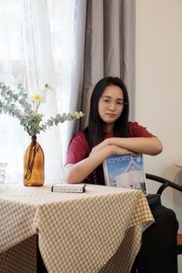 Portrait of young woman sitting on table