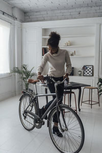 Mid adult woman leaving her home office, pushing bicycle