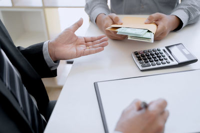 Midsection of man using smart phone on table