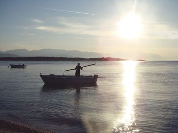 Silhouette man in sea against sky during sunset