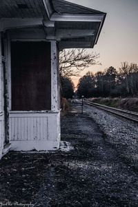 Empty road by abandoned building against sky