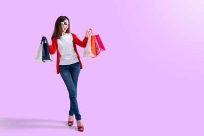 Full length of woman standing against pink background