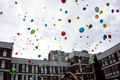 Low angle view of balloons against buildings in city