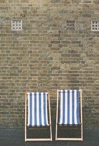 Empty chairs against brick wall