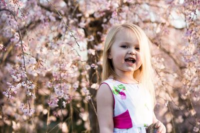 Portrait of cute girl standing against cherry blossom at park