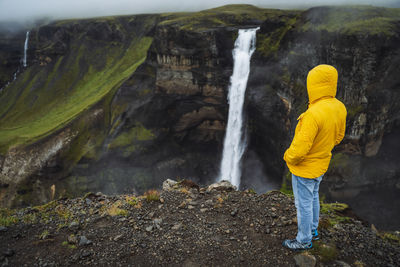 Rear view of man looking at waterfall