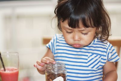 Close-up of cute girl with food in jar at home