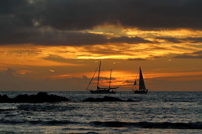 Silhouette sailboats in sea against sky during sunset