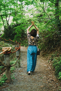 Rear view of woman standing in forest