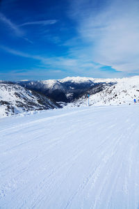 Scenic view of snow covered mountains against blue sky