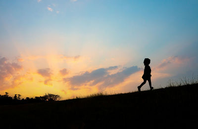 Silhouette person standing on field against sky during sunset