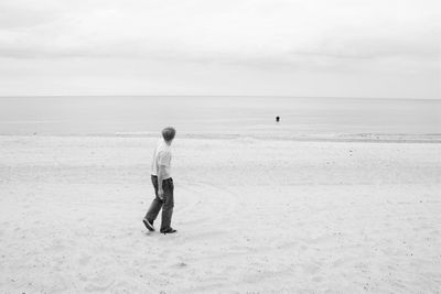 Rear view of people walking on beach