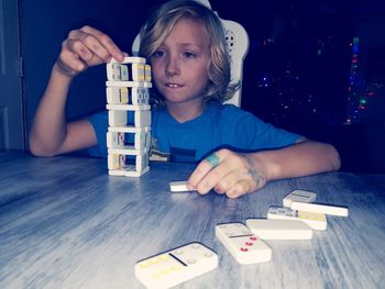 Boy playing with dominoes on table