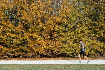 Man running on footpath by trees