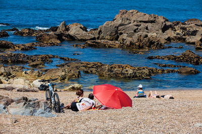 People sitting on rocks by sea