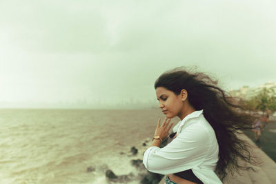 Young woman looking at sea against sky