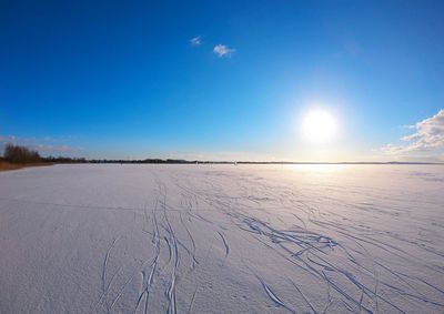 Snow covered frozen lake against blue sky