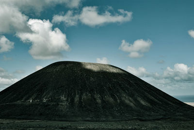 View of volcanic mountain against cloudy sky