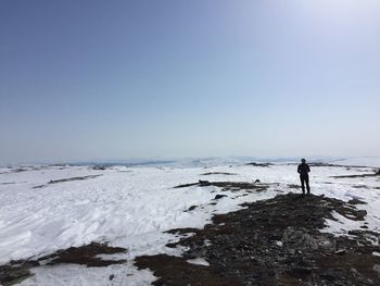 Man standing on snow covered land against clear sky