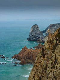 Scenic view of cliff and sea against sky