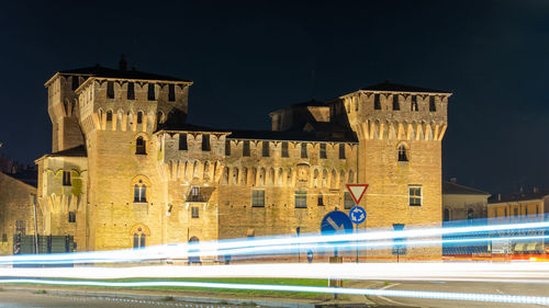 Light trails on building against sky at night