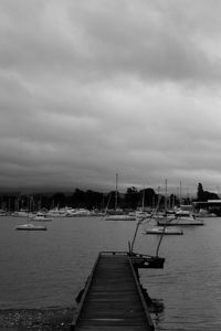 Pier on sea against cloudy sky