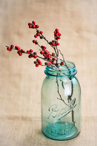 Close-up of rowanberries in jar on wooden table