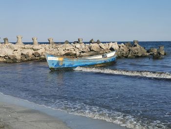 Boat moored on shore against clear sky