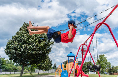 Side view of boy on a swing with playground in the background.