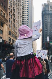 Rear view of woman standing on street in city