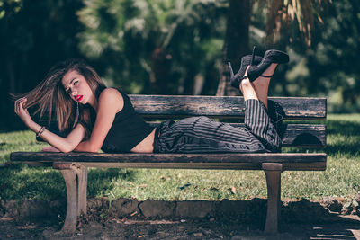 Portrait of woman lying down on bench in park