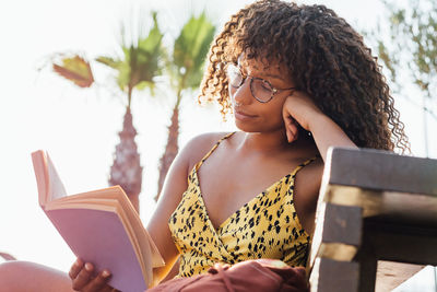 Young woman looking away while sitting on book