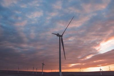 Low angle view of silhouette wind turbine against sky during sunset