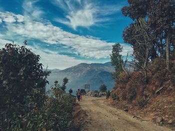 Rear view of man walking on mountain against sky