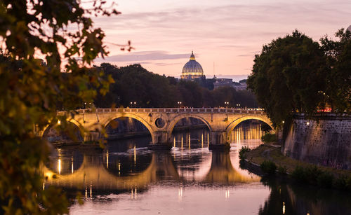 Arch bridge over river during sunset