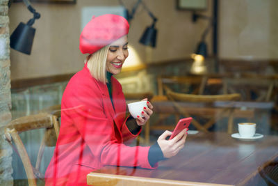 Young woman using mobile phone while sitting on chair