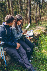 Young couple sitting on land in forest