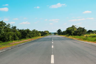 Empty road amidst trees against sky, the great east road, zambia 