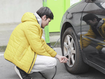 A young man spins a bearing in a car wheel.